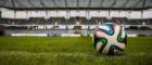 A football sitting on the grass of a football pitch with the stadium seating in the background. Source: School of Law