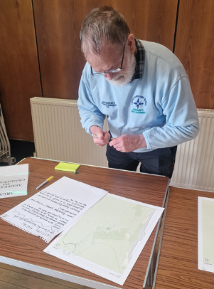 Image shows community member looking at maps during meeting