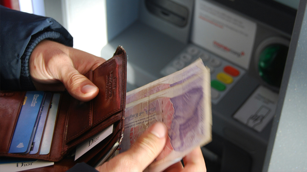 A close-up photo of a person taking money out of a wallet