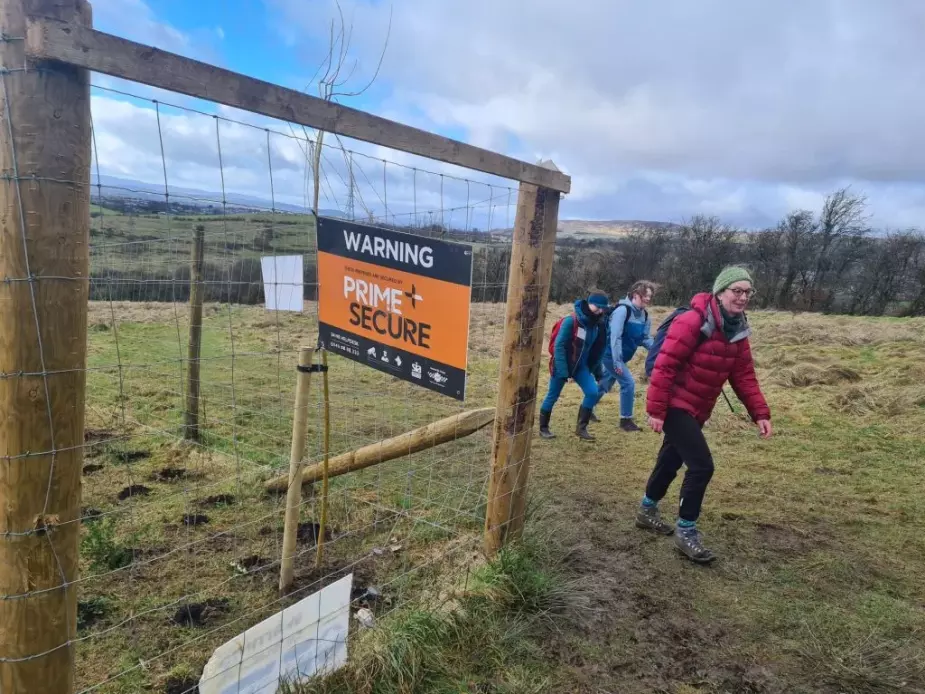 Bella Hoogeveen, Jennifer McArthur and Alison Phipps walking past a wire enclosure in a field