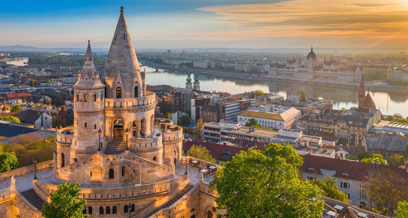 Beautiful golden summer sunrise with the tower of Fisherman's Bastion and green trees. Parliament of Hungary and River Danube in background [Photo: Shutterstock]