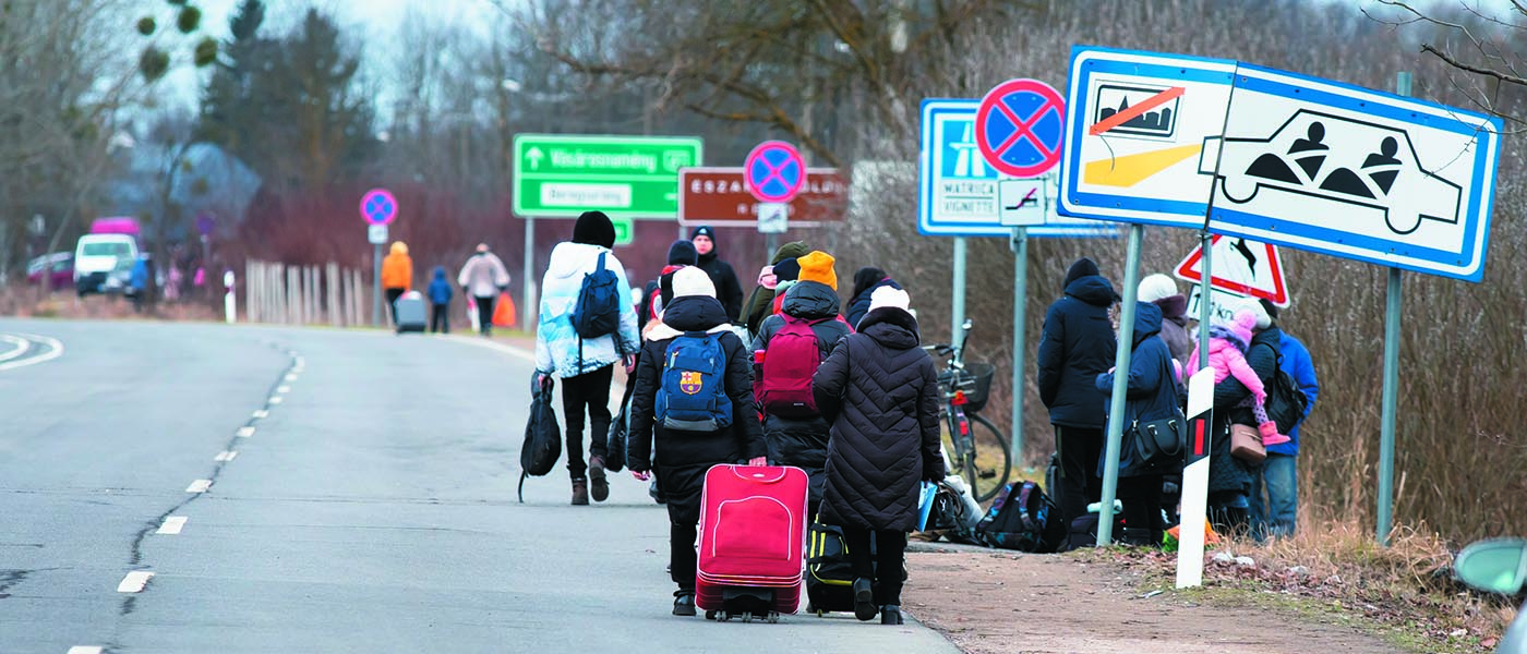 Migrants walking along a road with luggage