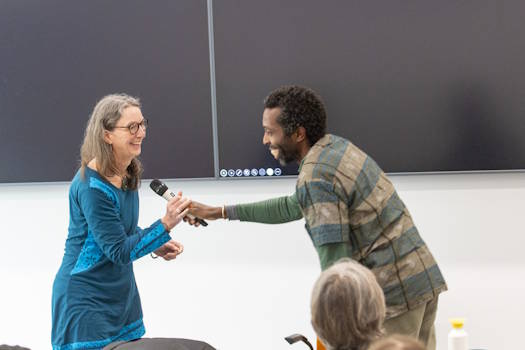 Tawona Sitholé passing a microphone to Alison Phipps