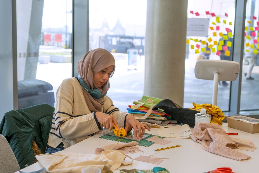 A woman works at a table with crafting materials