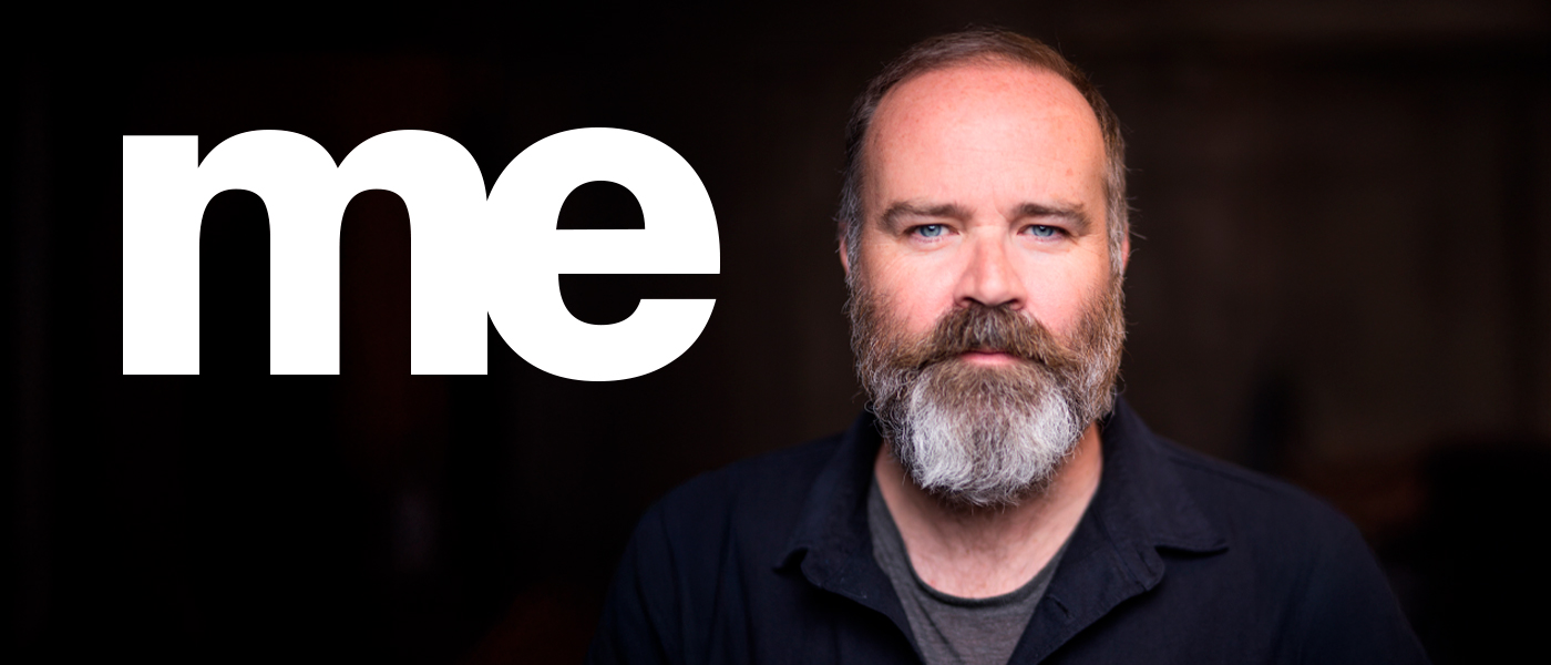 Headshot of Greg Hemphill on a dark background