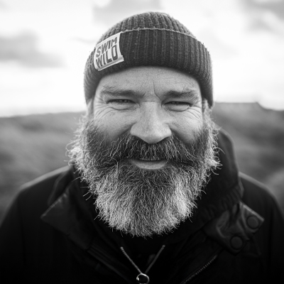 Black and white headshot of Greg Hemphill outside wearing a woolly hat