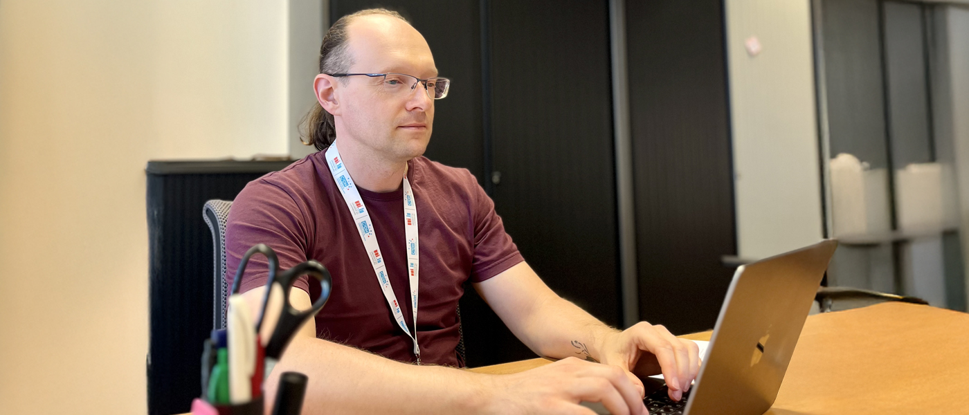 Vitalii Klymchuk at a desk on a laptop in his workplace