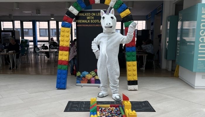 Unicorn mascot standing in front of Lego brick arch