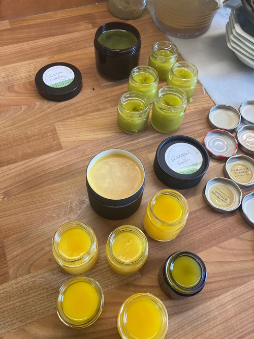 Photo of lots of small pots containing a yellow balm sat on a wooden countertop