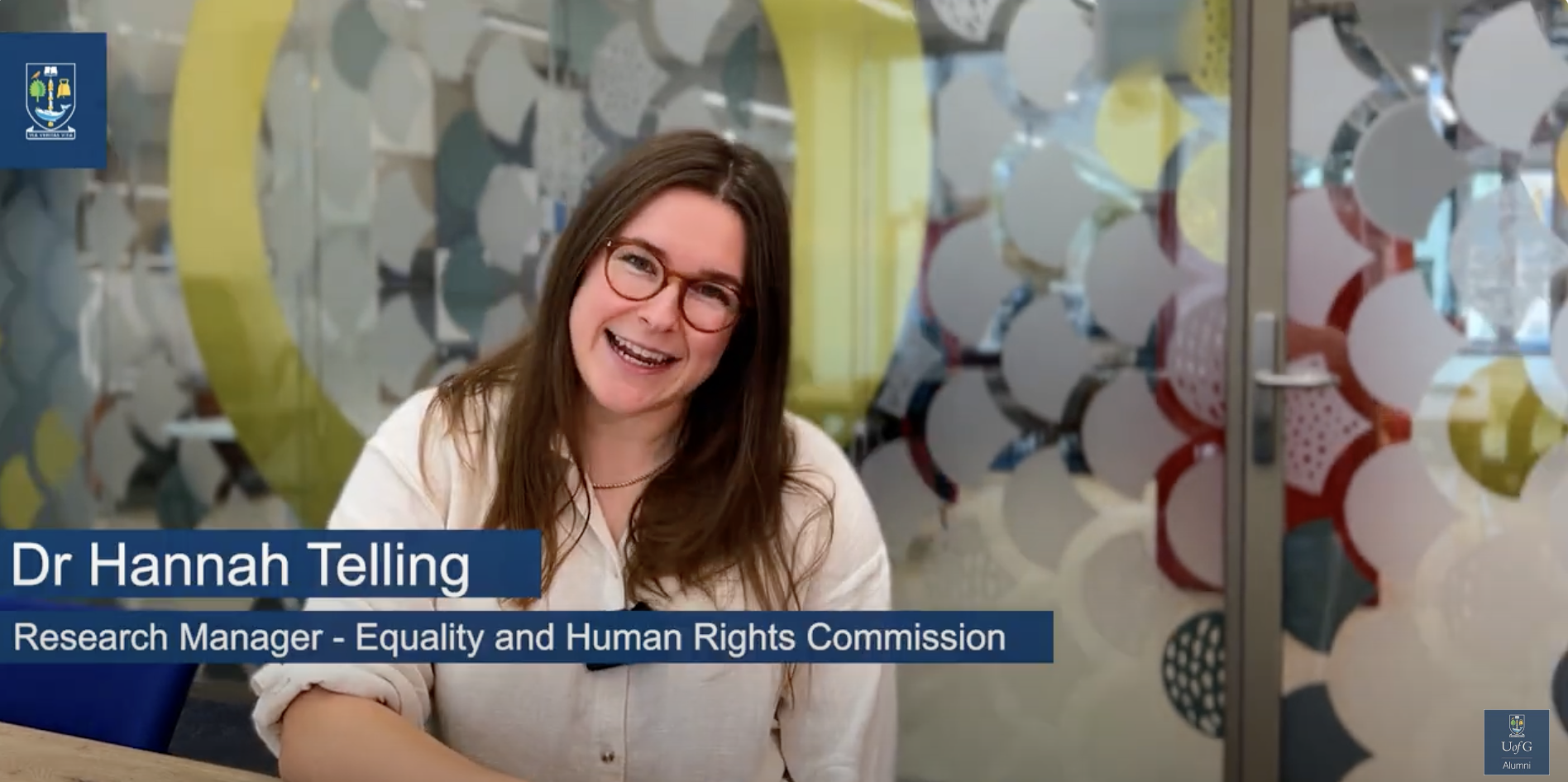 Still from UofG branded YouTube video of woman with brown hair, glasses and white blouse. Title says 'Dr Hannah Telling, Research Manager, Equality and Human Rights Commission'