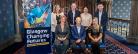 A group of people in two rows, four people standing, three sitting in front next to Glasgow Changing Futures pull-up banner