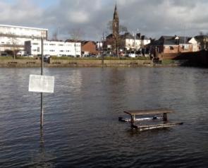 Bench in flood water, town in background