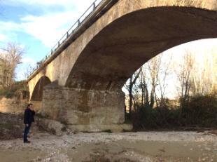 Man looking up at large bridge