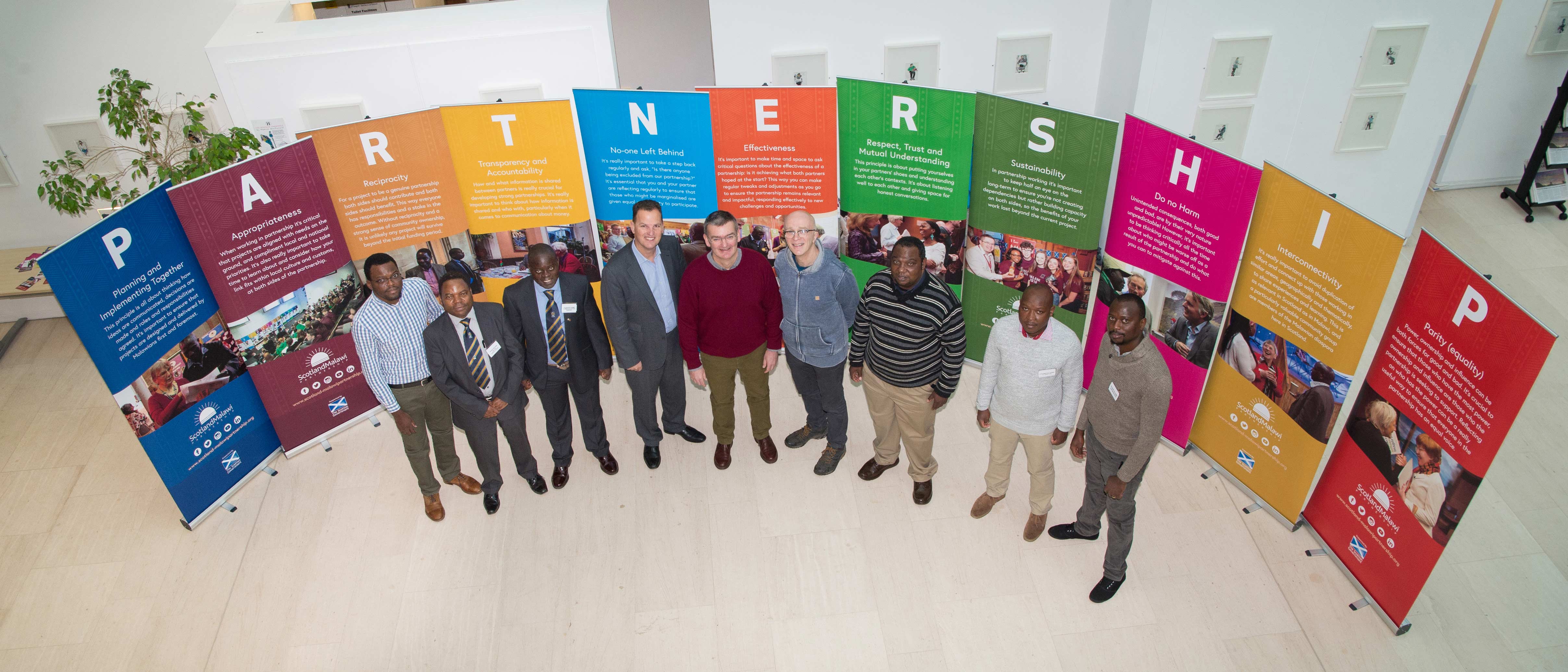 Group of people standing together in front of signs representing partnership