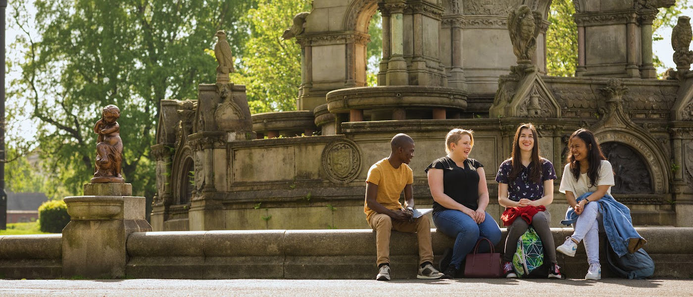 Group of four students sitting in front of the fountain in Kelvingrove Park