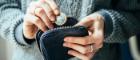 Someone holding a purse with their left hand and taking a pound coin out with the other hand. Image credit: iStockphoto | gregory_lee https://www.istockphoto.com/photo/currency-gm514780670-88262803