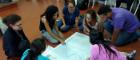 A group of people sitting on the floor examining a map and talking about it