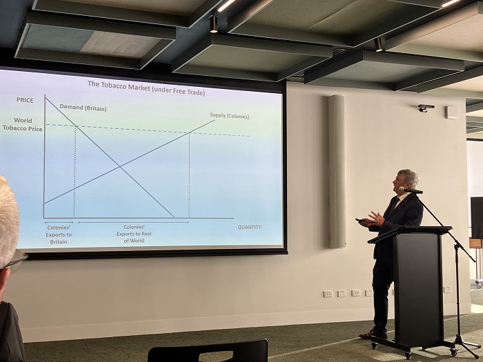 Speaker with a slide on a screen entitled The Tobacco Market (under Free Trade). Source: Australian National University  